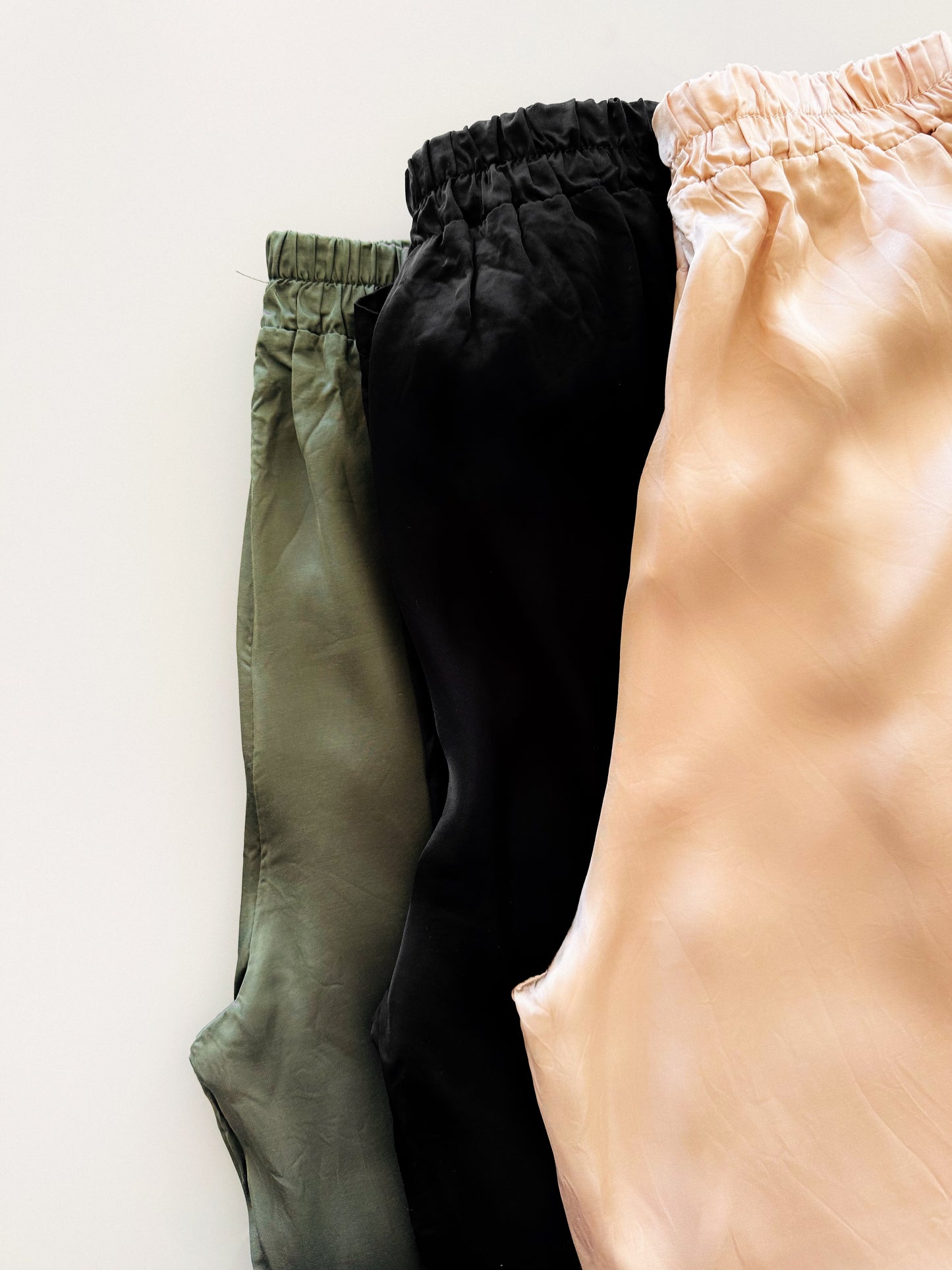 3 Satin Hose (Beige, Olive und Schwarz) flatlay artig fotografiert.