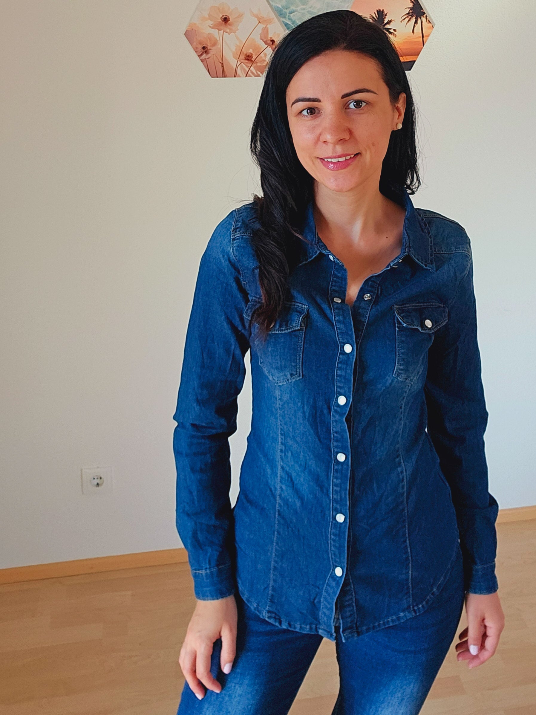 Das Model trägt eine dunkelblaue Jeansbluse mit Knopfleiste und Brusttaschen.