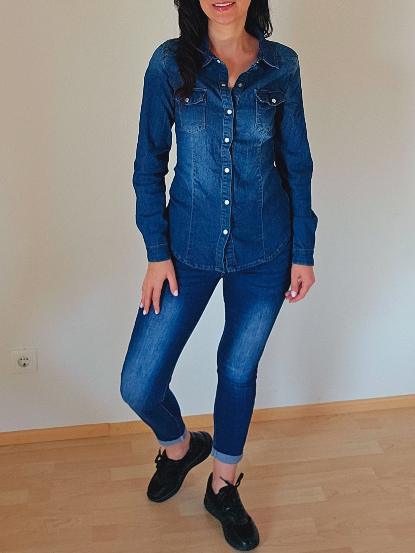 Das Model trägt eine dunkelblaue Jeansbluse mit Knopfleiste und Brusttaschen.