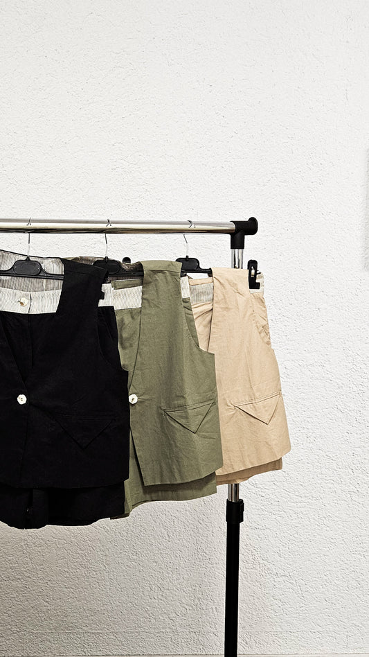 Auf dem Bild 3 Sets sind aufgehängt zu sehen. Schwarz, oliv und hell beige Weste mit Knopfverschluss und V-Ausschnitt, dazu passende kurze Hose.